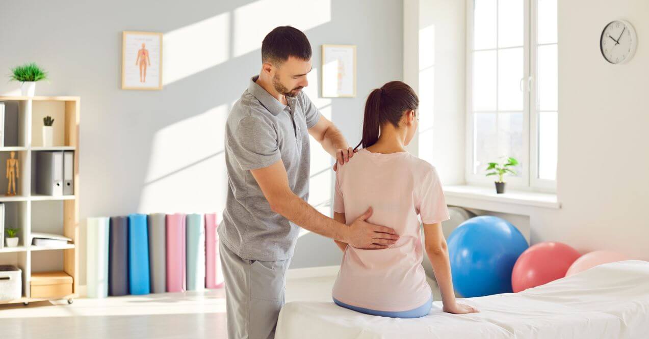 Chiropractor adjusting woman's back in therapy room