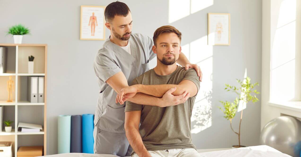 Physical therapist assisting man with shoulder exercise