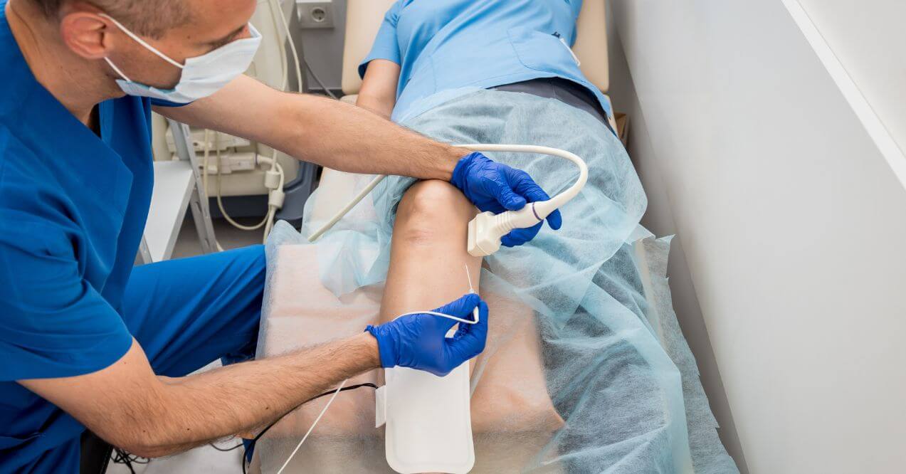Doctor performing radiofrequency ablation on patient's leg