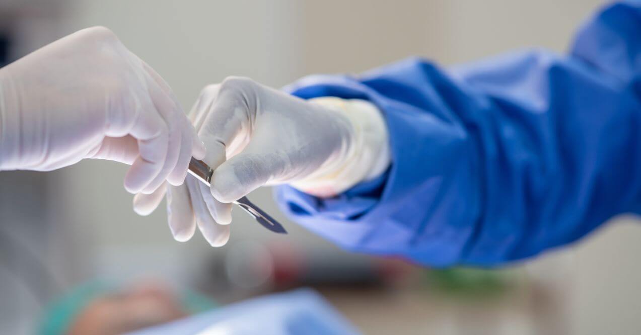 Surgeon receiving scalpel during operation in sterile environment