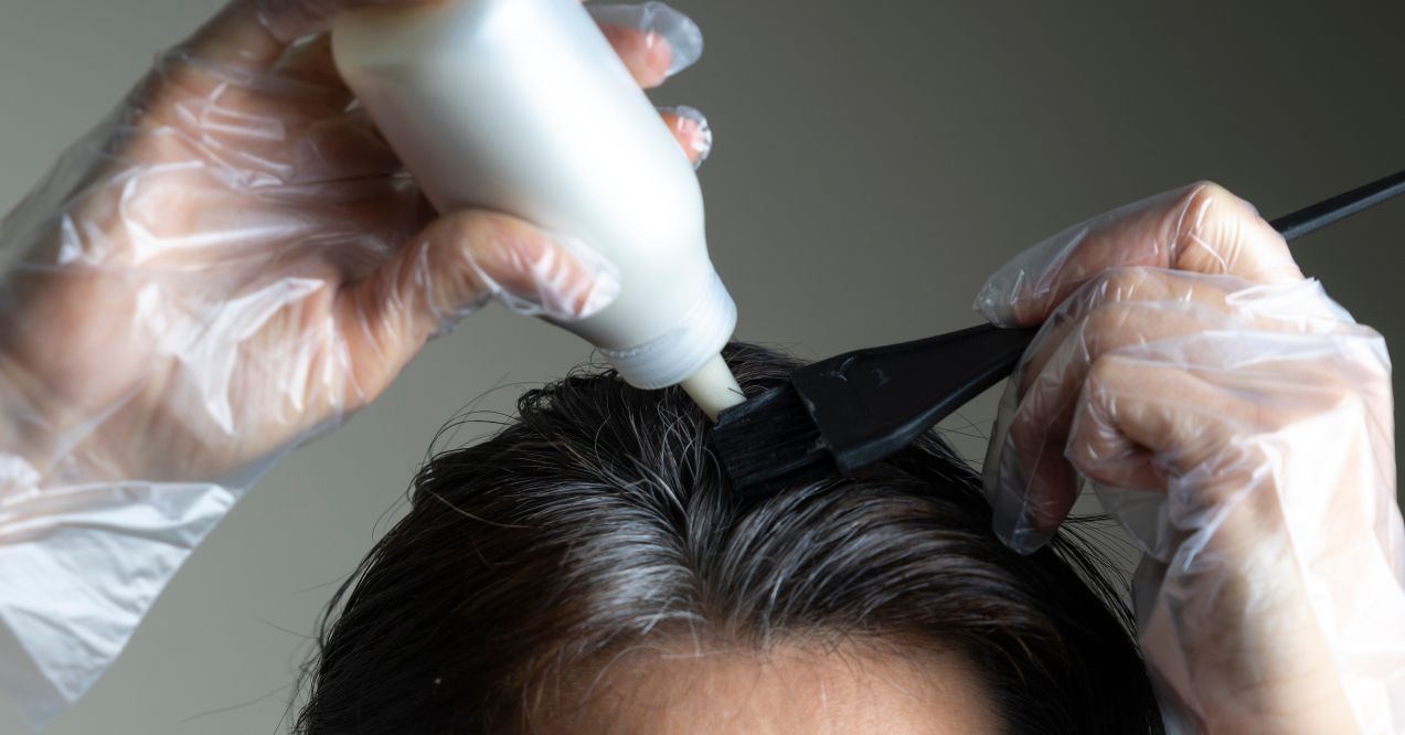 Applying hair dye to roots with gloved hands resembling does hair dye cause hair loss topic