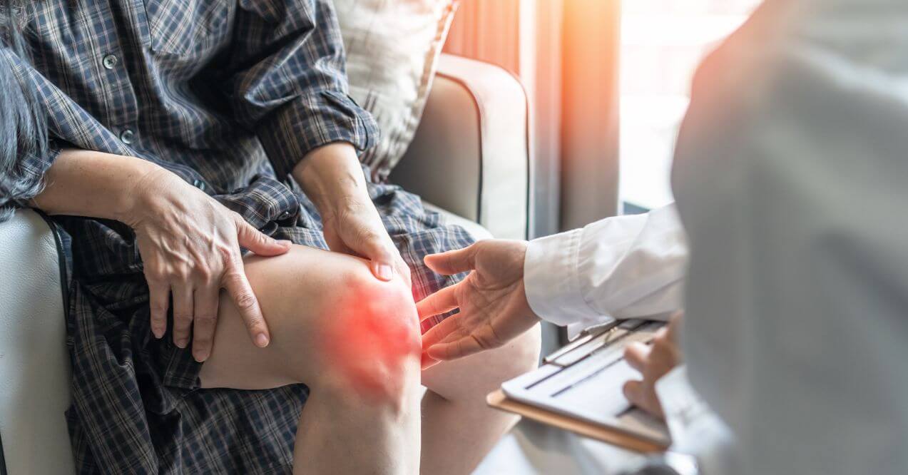 Doctor examining a patient’s painful knee with red inflammation highlight