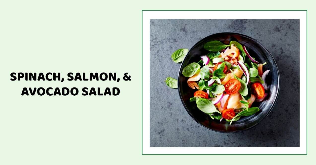 Colorful spinach, salmon, and avocado salad served in a black bowl.