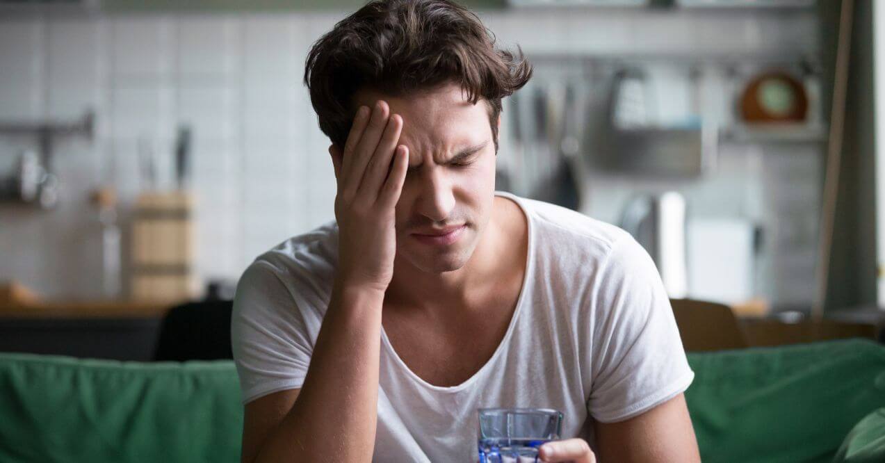 Man holding forehead with eyes closed, feeling dehydration brain fog