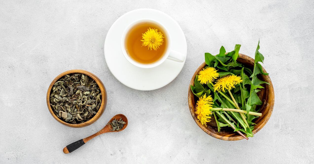 Dandelion tea in a white cup with dried leaves and fresh greens in wooden bowls representing the topic how to make dandelion tea