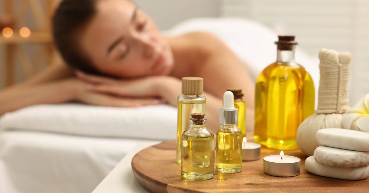 Essential oils for lymphatic drainage arranged with stones, candles, and flowers on a wooden tray