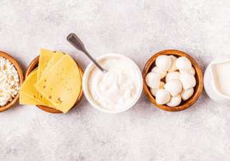 Variety of dairy products including cheese, cottage cheese, yogurt, mozzarella balls, and milk in bowls.